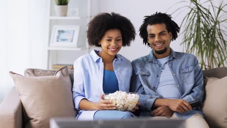 lächelnde-Paar-mit-Popcorn-zu-Hause-vor-dem-Fernseher