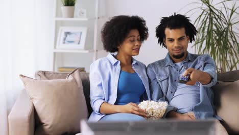 lächelnde-Paar-mit-Popcorn-zu-Hause-vor-dem-Fernseher