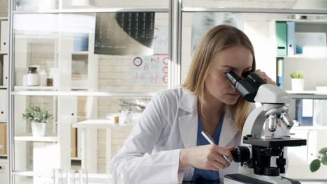 Mujer-en-bata-de-laboratorio-con-microscopio