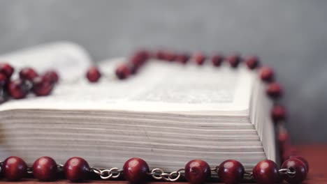 Bible-and-the-crucifix-beads-on-a-red-wooden-table.-Beautiful-background.-Religion-concept-close-up