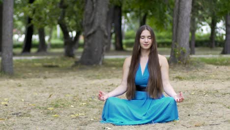 Hermosa-mujer-en-vestido-azul-medita-al-aire-libre,-lugar-para-el-texto-del-anuncio,-dolly-shot