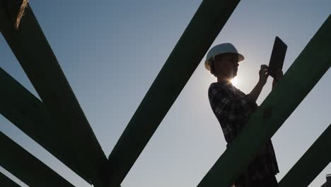 Un-arquitecto-femenino-está-trabajando-con-una-tableta-en-el-techo-de-una-casa.-Técnico-y-control-de-autor-en-la-construcción