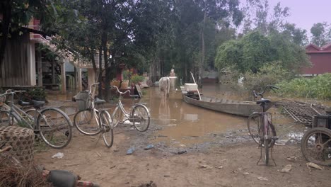 Granjero-que-se-lleva-una-vaca-en-el-campo-a-través-de-un-pueblo-inundado-durante-la-temporada-de-Monzón