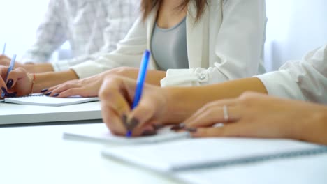 Closeup-jungen-männlichen-und-weiblichen-Studenten-Hände-schreiben-mit-Stiften-in-Notebook-im-Klassenzimmer