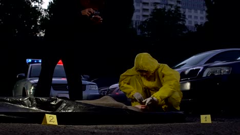 Forensics-expert-and-police-officer-working-at-crime-scene,-taking-photos