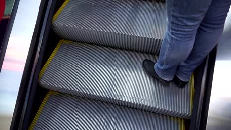 Frauen-die-Beine-in-Stiefeln-und-Jeans,-die-Rolltreppe-hinauf.