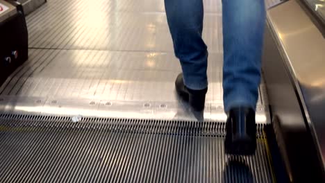 Women's-legs-in-boots-and-jeans,-going-up-the-escalator.