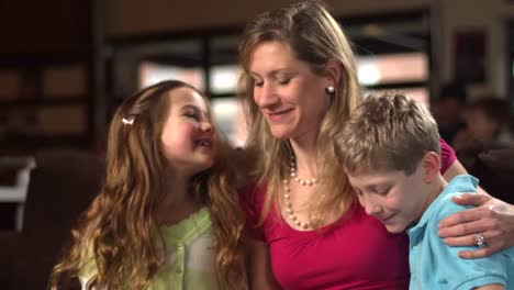 A-mother-hugs-her-son-and-daughter-as-they-sit-in-the-house-reading