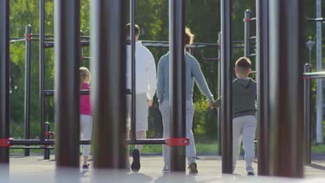 Deportivos-padres-caminando-con-los-niños-en-el-patio-de-entrenamiento-al-aire-libre