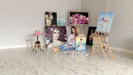 A-talented-girl-artist-sits-on-the-floor-among-the-many-of-his-paintings.