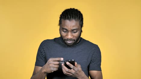 Online-Shopping-auf-Smartphone-von-Casual-afrikanischen-Mann-auf-gelbem-Hintergrund-isoliert