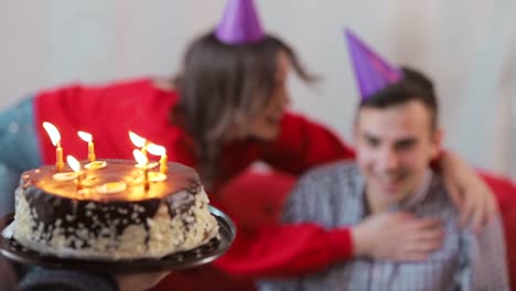 Handsome-man-blowing-birthday-candles-while-close-friends-throwing-a-surprise-party,-slowmotion-in-cozy-modern-apartment