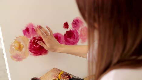 Close-up-of-the-artist's-girl's-hand-on-the-canvas,-she-draws-flowers.