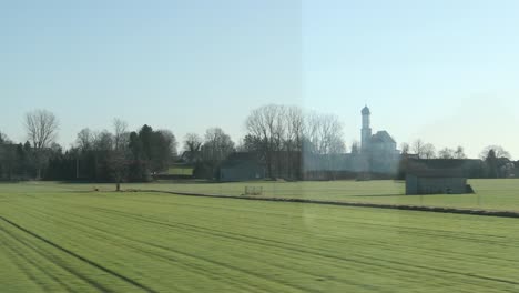 Landschaft,-die-durch-Zugfenster-gesehen