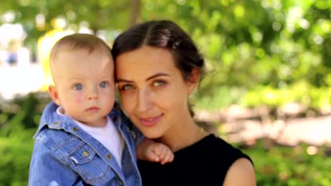 A-young-happy-mother-walks-with-her-newborn-son-in-the-park-in-the-summer.