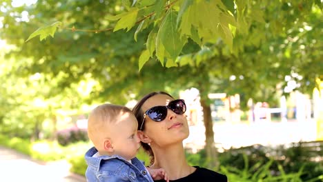 Eine-junge-glückliche-Mutter-geht-mit-ihrem-neugeborenen-Sohn-im-Park-im-Sommer.