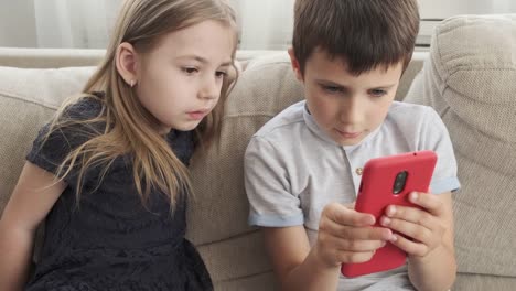 Niños-pequeños-jugando-juego-en-el-teléfono-móvil