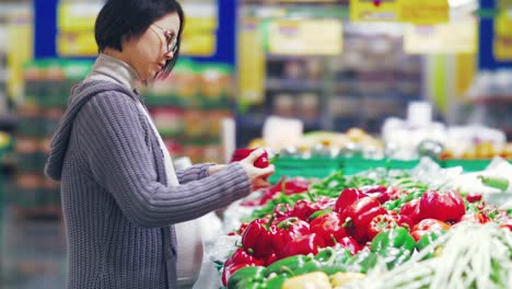 Mujer-asiática-embarazada-comprando-en-el-mercado-fresco