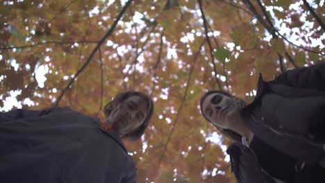 Hombre-y-mujer-en-trajes-de-Halloween-mirando-hacia-abajo-en-la-víctima-con-caras-de-miedo-graves-en-el-parque-de-otoño