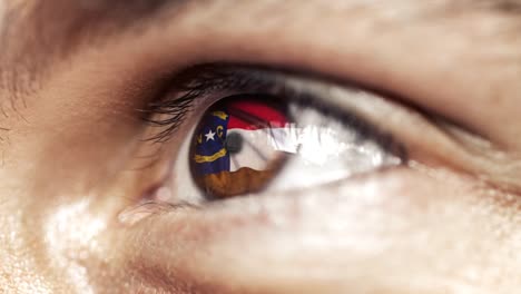 Man-with-brown-eye-in-close-up,-the-flag-of-North-Carolina-state-in-iris,-united-states-of-america-with-wind-motion.-video-concept