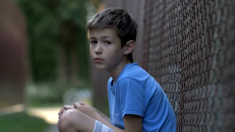 Sad-upset-abused-teenager-boy-sitting-alone,-lonely-homeless-boy,-pain-on-face