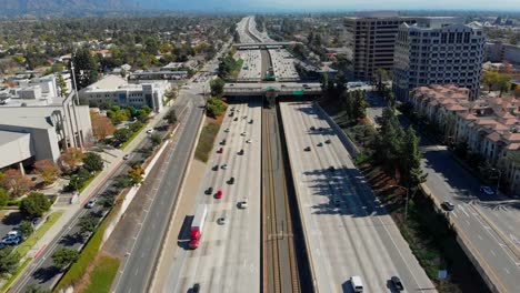 Aerial-Shot-aufsteigend-schnell-über-210-Freeway,-zeigen-viele-Häuser,-eine-Tankstelle,-Berge,-Gebäude-und-eine-Kirche-in-Pasadena,-Kalifornien