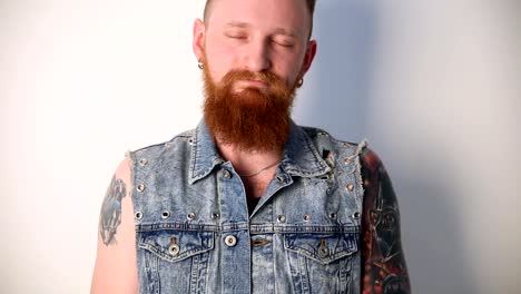 modern-youth.-calm-portrait-of-a-good-biker-with-tattoos-and-a-stylish-beard-and-mustache-in-a-denim-waistcoat.