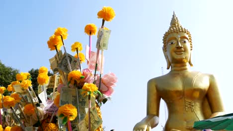 Thai-paper-money-on-a-branch-of-the-Marigold-on-the-background-of-big-golden-Buddha,-Pattaya.-Thailand