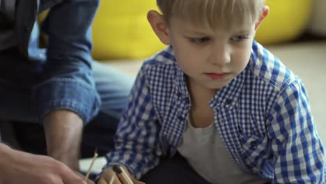 Upset-Little-Boy-Making-House-Model-with-Dad