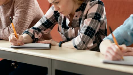 Moving-Footage-of-a-Row-of-Multi-Ethnic-Students-in-the-Classroom-Taking-Exam/-Test/-Writing-in-Notebooks.-Bright-Young-People-Study-at-University.