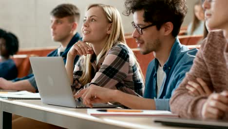 In-der-Klasse-weibliche-und-männliche-Studenten-teilen-und-Laptop,-auf-einem-Vortrag-im-Chat-nutzen.-Junge-Menschen-studieren-und-lernen.-Uni-Leben.