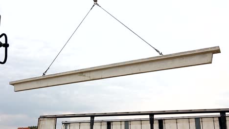 Worker-is-attaching-crane-hooks-to-concrete-joist-in-truck-trailer