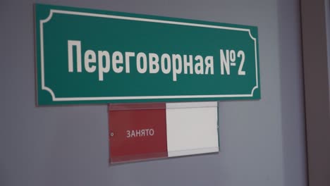 Female-hand-moves-paper-to-free-on-door-with-cyrillic-text-meeting-room