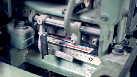 Factory-machine-is-shearing-excessive-part-of-coloured-newspapers