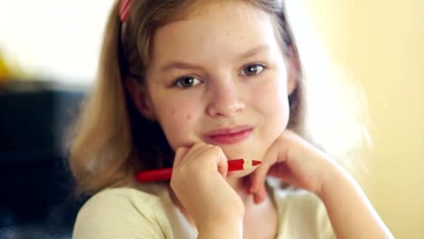 Porträt-von-einem-schönen-lockigen-Mädchen-hautnah.-Eine-Schulmädchen-befasst-sich-mit-der-Kamera-und-lächelt.-Das-Mädchen-hat-einen-roten-Stift-in-der-Hand.-Zurück-zur-Schule.-Tag-des-Wissens