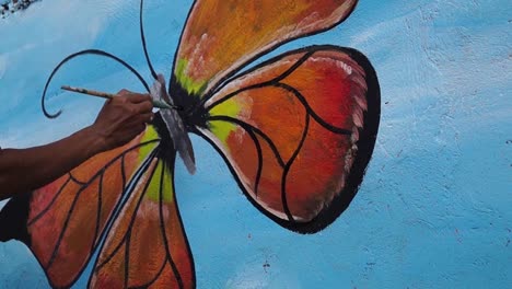 Mural-painter-paints-butterfly-in-color-on-school-wall.-time-lapse