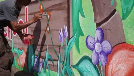 Mural-painter-paints-a-garden-image-in-color-on-the-school-wall.-time-lapse