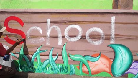 Mural-painter-draws-a-letter-S-on-school-wall.-time-lapse