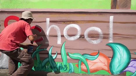 Mural-painter-draws-a-letter-c-on-school-wall.-time-lapse