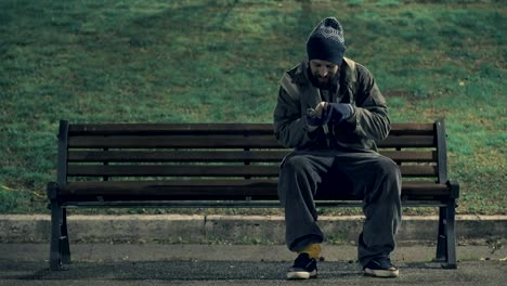 Obdachlose-sitzen-auf-Bank-in-der-Nacht-sein-Geld-zählen