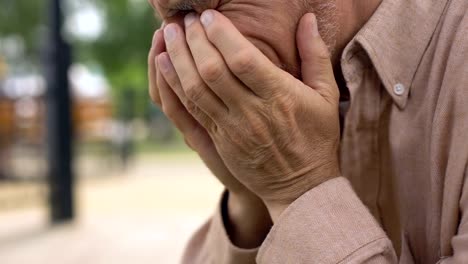 Aged-pensioner-crying-close-up,-covering-face-with-hands-in-despair,-sorrow