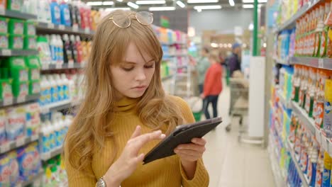 Frauen-im-Supermarkt-einkaufen-und-mit-mobilen-apps-auf-ihrem-tablet