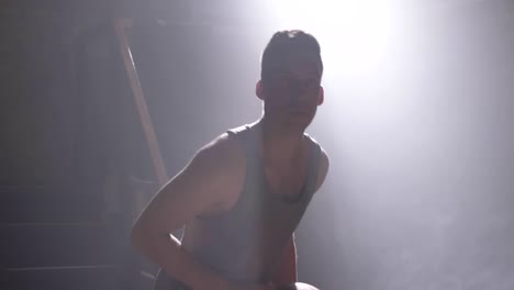 Tall-man-performing-basketball-slam-dunk-in-dark-gym-with-smoke