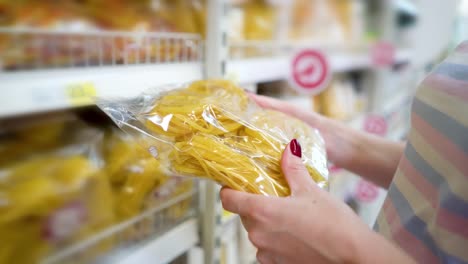 Closeup-caucasian-woman-near-shop-shelves-and-choosing-pasta-in-grocery-market