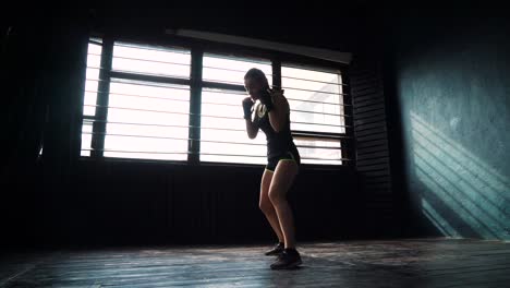 silueta-de-joven-hermosa-mujer-boxeo-entrenamiento-en-gimnasio-de-perforación