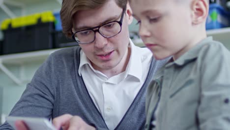 Man-Teaching-Boy-to-Use-Tablet