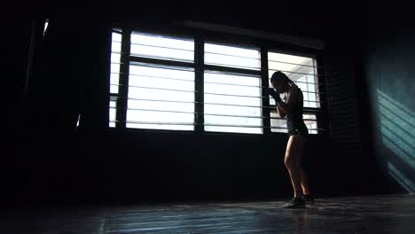 silhouette-beautiful-young-boxing-woman-training-punching-in-fitness-studio-slow-motion