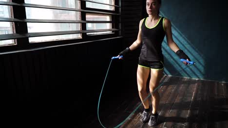 Slow-Motion-junge-ernsthafte-Boxerin-in-umschlossenen-Händen-Aufwärmen,-springen-auf-Springseil-im-Fitness-Studio