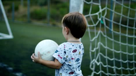 Kleiner-Junge-hält-den-Ball-in-seine-Hände-auf-dem-Fußballplatz