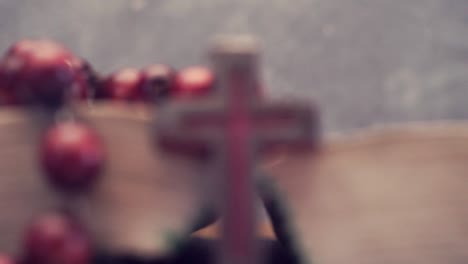 Open-Bible-and-the-crucifix-beads-on-a-golden-table,-close-up.-Beautiful-dark-background.-Religion-concept